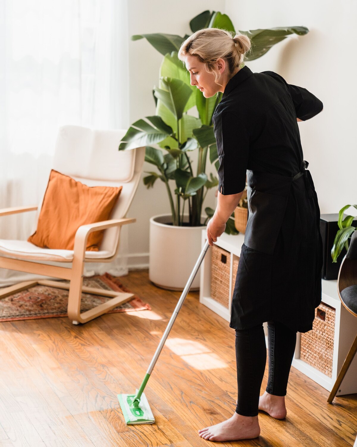 Cleaner mopping a bright furnished living area