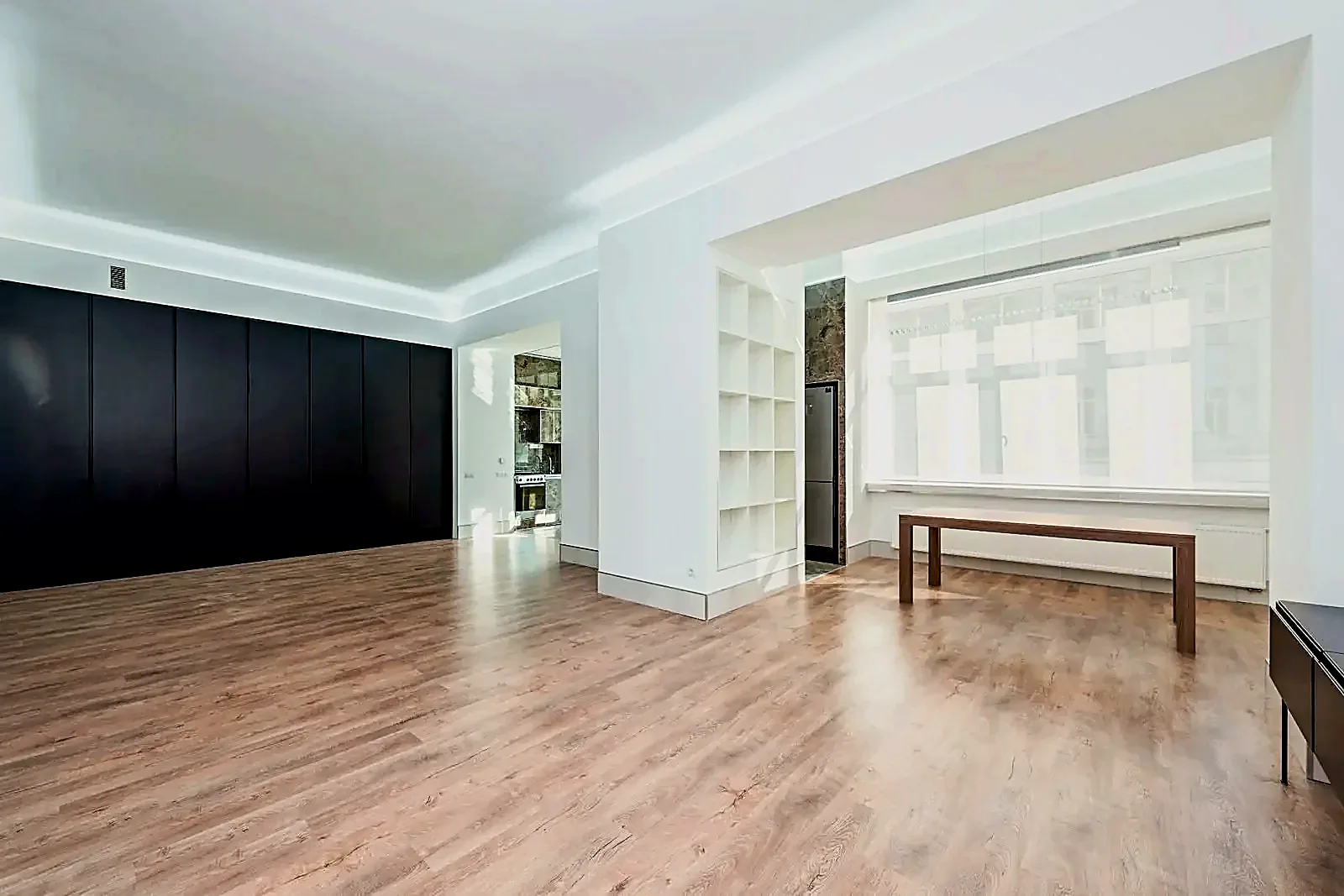 Bright, polished empty home interior with clean floors, built-in storage, and a large window