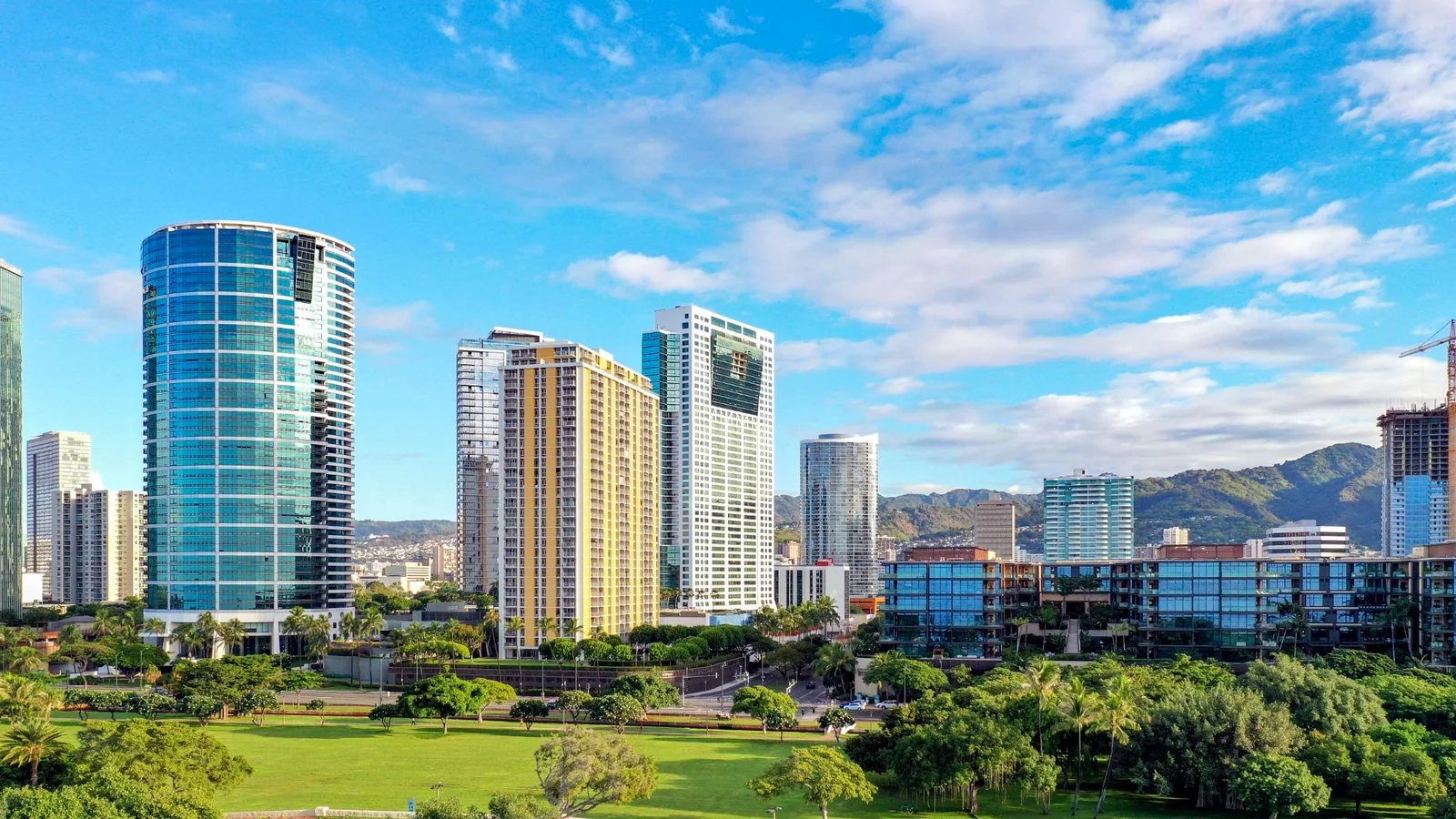 Honolulu skyline, green park, and Koʻolau foothills on Oʻahu under a bright blue sky